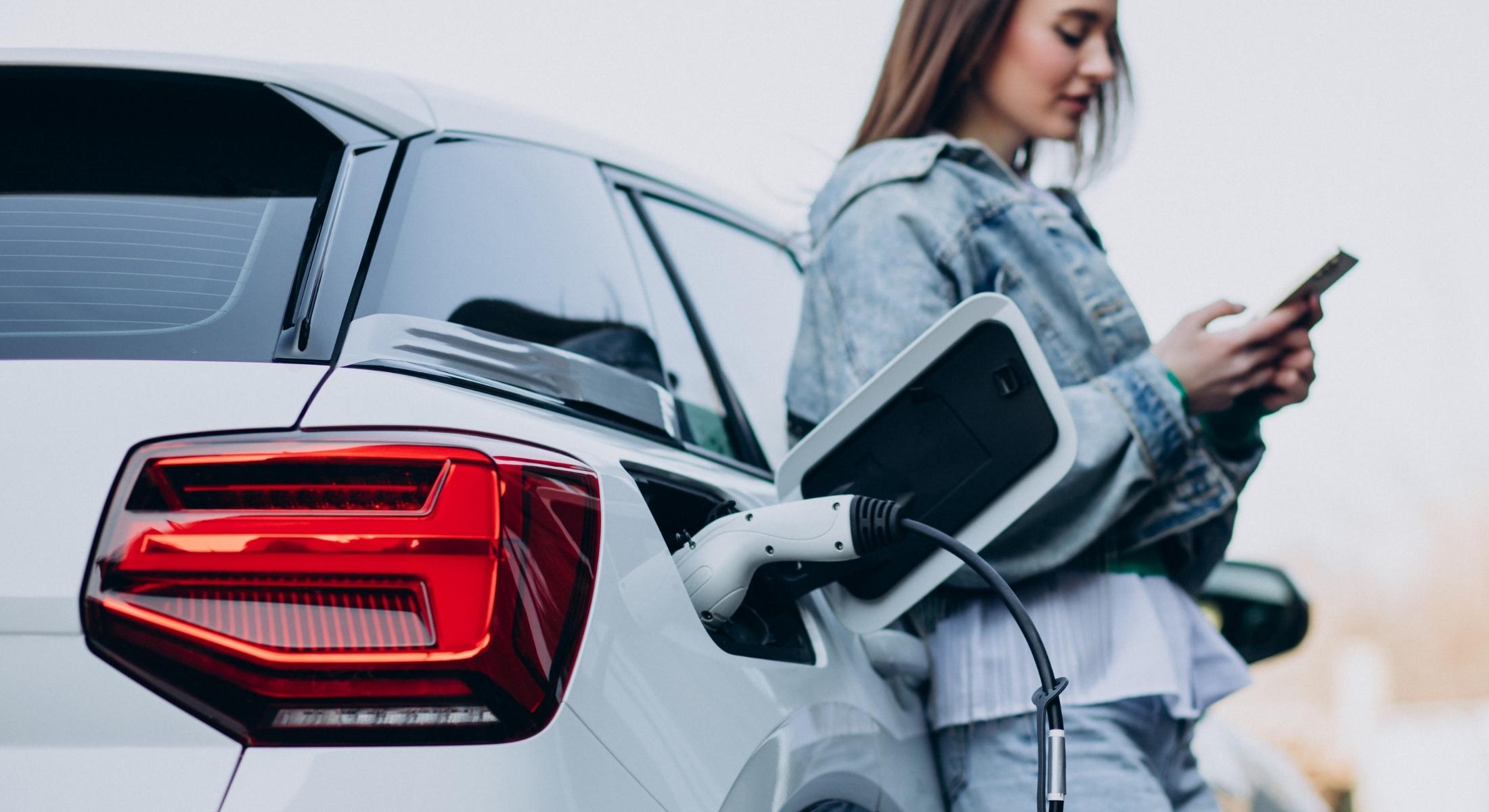 Junge Frau mit Smartphone in der Hand lehnt an ihr