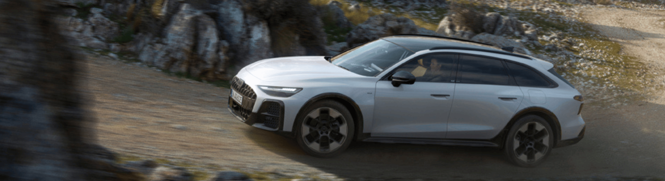 Grauer Audi A6 allroad fährt eine steinige Straße