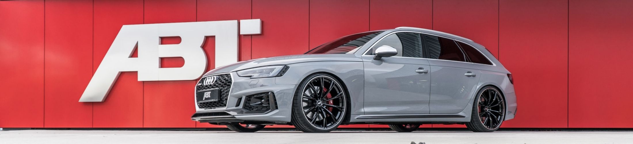 Ein grauer Audi vor dem ABT Logo