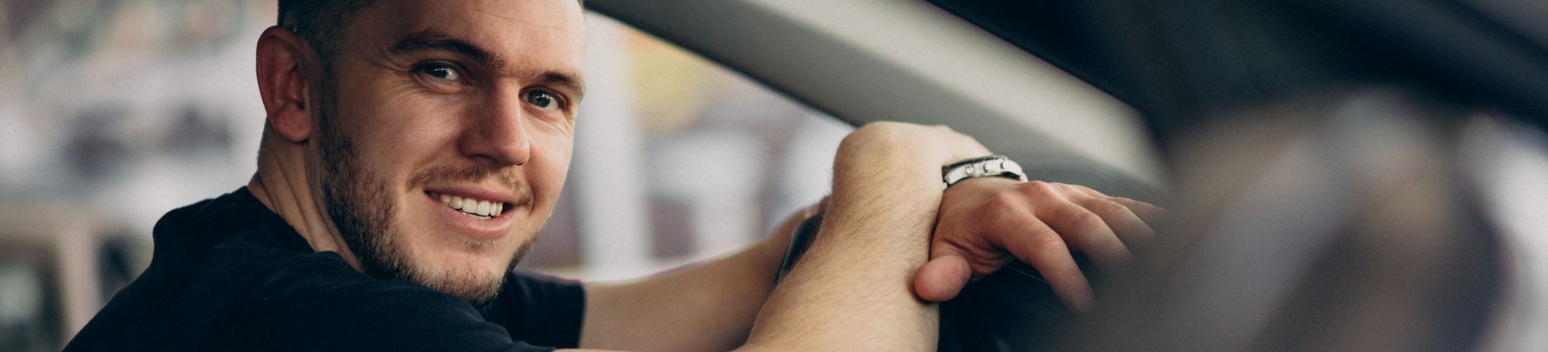 Nahaufnahme l&auml;chelnder Mann in seinem Auto