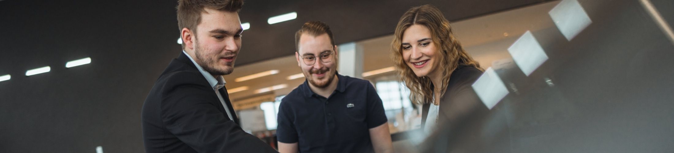 Drei Personen im Gespr&auml;ch, &uuml;ber ein Auto